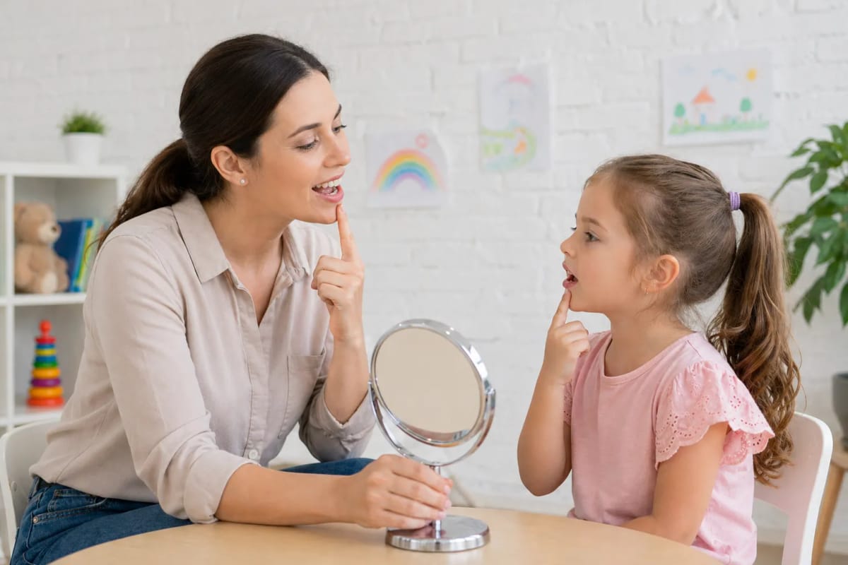 Speech therapist helping child practice articulation and pronunciation during pediatric speech therapy session at rehabilitation clinic